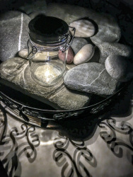 a solar lantern, some big and small stones, shadows and a black metall bowl