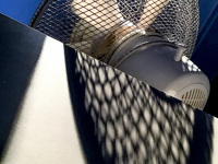 a white ventilator with a blue background is casting a big shadow