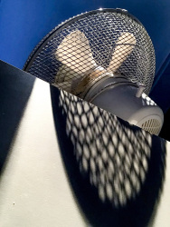 a white ventilator with a blue background is casting a big shadow