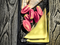 a plate with cheese, ham, tomatoes and two wasps is standing on a wooden table