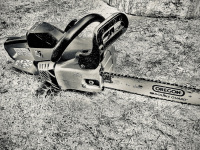 a chainsaw in front of wood to be sawn, black-and-white