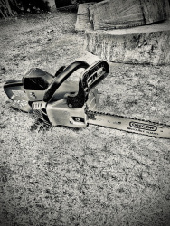 a chainsaw in front of wood to be sawn, black-and-white