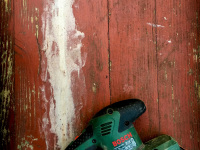 a green bosch grinding machine on a red wooden table in need of renovation