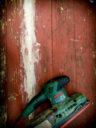 a green bosch grinding machine on a red wooden table in need of renovation