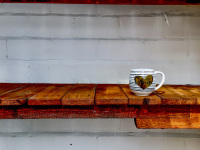 a coffeecup with a golden heart is staying in a light brown shelf