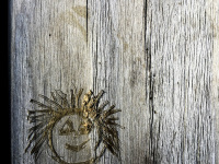 in a grey wood there is carved a funny face into it