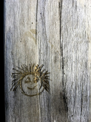 in a grey wood there is carved a funny face into it