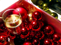 a full glass of sparkling wine is standing between red, green and golden christmas balls