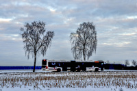 an articulated bus is driving on a street through a snowy winter landscape in hermannsburg
