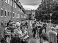 a little group of citizens and politicians is visiting an uninhabited residential area in unterlüß, black-and-white