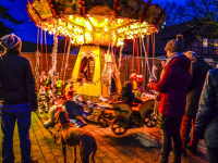 in a winterly evening light familys are standing round a carousel on a christmas market in hermannsburg