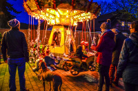 in a winterly evening light familys are standing round a carousel on a christmas market in hermannsburg