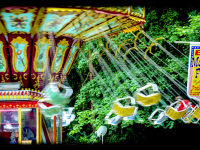 a chain carousel at a funfair in faßberg is turning around in front of green trees