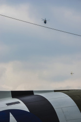 at a military day in faßberg a transport helicopter and a little dragon fly are flying over an old military aircraft
