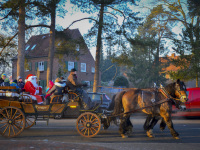 in wintry evening sun a horse-drawn carriage is driving with santa claus through the streets of faßberg