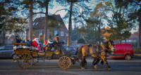 in wintry evening sun a horse-drawn carriage is driving with santa claus through the streets of faßberg