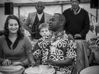 at a festival of the evangelical mission in hermannsburg a man and a woman are playing bongos, a little boy looks at it