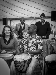 at a festival of the evangelical mission in hermannsburg a man and a woman are playing bongos, a little boy looks at it