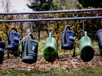 green and blue watering cans are hanging on a black steel railing at a cemetry in bergen in lower saxony
