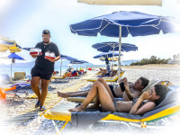 at the beach in charaki on rhodes a young greek is bringing frappé for young people who are laying under umbrellas