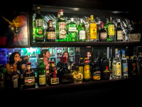 female guests are reflected in a mirror behind many bottles of alcohol in the rockbar sticky fingers in rhodes city