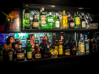female guests are reflected in a mirror behind many bottles of alcohol in the rockbar sticky fingers in rhodes city