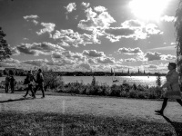 people are walking at the alster shore in hamburg by a sunny sky with some clowds, black-and-white