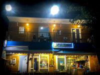 the nightly view on the tavern yamas in stegna on rhodes shows downstairs the owner at the grill and upstairs customers at eat