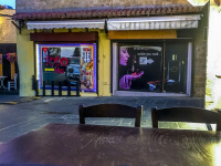 in front you see an empty wooden table with chairs and in the background two store windows in an empty street in the old town of rhodes in the evening