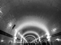 view in the old tunnel under the elbe in hamburg where people are going for a walk, black-and-white
