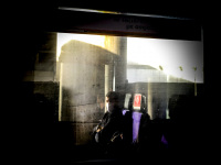 someone with a mask is reflecting in the window of a train between athens and patras