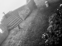 a little boy is running over a plattform of the castello della guaita in san marino, black-and-white