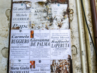 obituary notices on posters are hanging on a wall in the village bovino in puglia