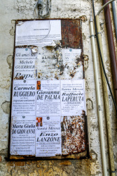 obituary notices on posters are hanging on a wall in the village bovino in puglia