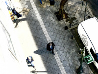 from the balkon of the attalos hotel in athens you see the street with some people, a tree and a white van