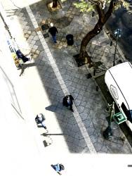 from the balkon of the attalos hotel in athens you see the street with some people, a tree and a white van