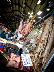 a lot of raw meat and offals is hanging in the halls of the central market in athens