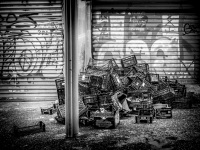 empty sales baskets from the central market in athens are piled up in front of a wall with graffiti, black-and-white