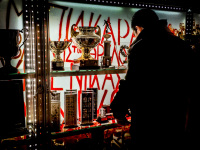 a young man is watching a show case in the museum of fc olympiakos piraeus inter alia with trophies of the club