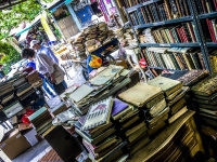two people rummage in piles of books at a shop of antiquarian in monastiraki in athens