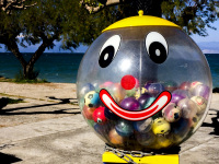 a sweets machine with a smily face on it is standing at promenade in diakopto