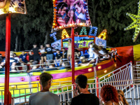 three people are looking at a rotating carousel on a funfair in kremasti on rhodes