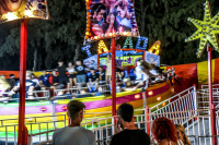 three people are looking at a rotating carousel on a funfair in kremasti on rhodes