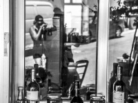 the reflexion of a window shows two persons who are making photos in the village agios isidoros on rhodes, black-and-white