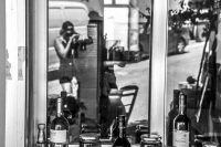 the reflexion of a window shows two persons who are making photos in the village agios isidoros on rhodes, black-and-white