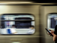 two young men at their phones at the metro in athens - one in front of the passing train and the other one as a reflexion in the trainwindow