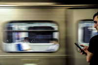 two young men at their phones at the metro in athens - one in front of the passing train and the other one as a reflexion in the trainwindow