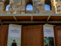 in front of the herodes atticus theatre in athens standing wooden walls with placards of greek musicians
