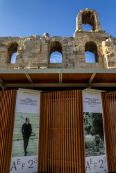 in front of the herodes atticus theatre in athens standing wooden walls with placards of greek musicians