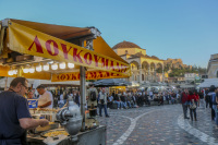 a stand with fresh baking loukoumades and many people on the monastiraki square in athens